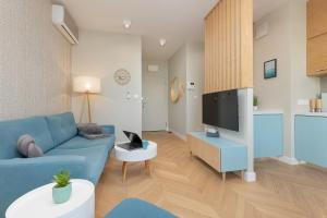 a living room with a blue couch and a tv at Bright Blue Apartment with Balcony, Parking and Air Conditioning in Warsaw by Renters in Warsaw