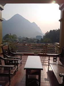 a balcony with tables and chairs and a view of a mountain at Hải Phận Homestay in Ha Giang