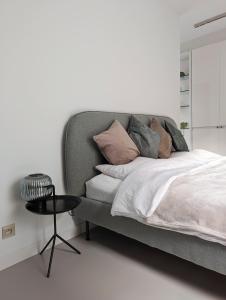 1 dormitorio con cama con almohadas y mesa en Spacious and cosy apartment near Berchem Station, en Amberes