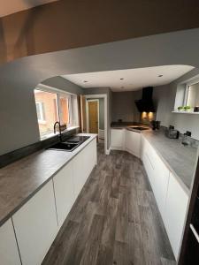 a kitchen with white cabinets and a wooden floor at Luxurious 2 Bedroom Private Detached Cottage in Llanddulas