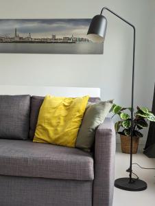 a couch with a yellow pillow next to a lamp at Spacious and cosy apartment near Berchem Station in Antwerp