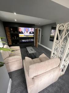 a living room with two white chairs and a flat screen tv at Luxurious 2 Bedroom Private Detached Cottage in Llanddulas