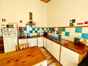 a kitchen with white cabinets and blue and white tiles at Sea Roots "Garden Zone " in Mosteiros