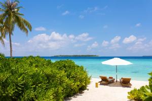 a beach with two chairs and an umbrella and the ocean at Emerald Faarufushi Resort & Spa - Deluxe All Inclusive in Raa Atoll