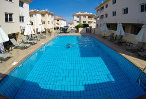 uma grande piscina azul num pátio com edifícios em 3 bed, Kapparis, Thea - 3A em Paralimni