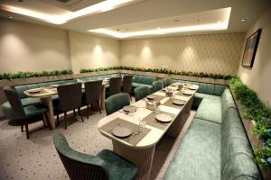 Mohali的住宿－Hiraya Hotels，餐厅设有长桌和绿色椅子