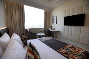 Habitación de hotel con cama y TV de pantalla plana. en Hiraya Hotels en Mohali