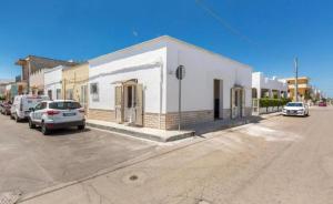 a white building with cars parked in a parking lot at La Casetta Al Mar in Porto Cesareo