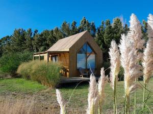 a wooden cabin in a field with tall grass at Experiencia única : Paz y naturaleza in Punta Colorada