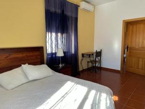 1 dormitorio con cama, mesa y ventana en La casa barata, casa rural, en Cedillo