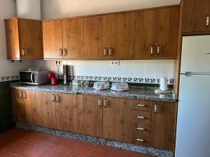 a kitchen with wooden cabinets and a white refrigerator at La casa barata, casa rural in Cedillo