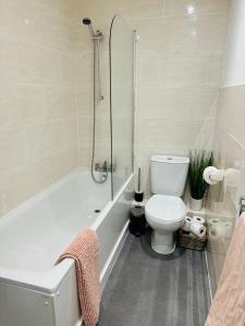 a bathroom with a toilet and a bath tub at Jubilee Rooms 15 Minutes Central London in London