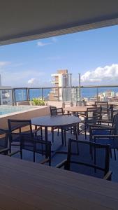 a patio with tables and chairs and a view of the ocean at Barra Caravela Studio in Salvador