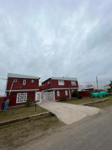 a red house with a driveway in front of it at Hostal Del Sol Temporario in Rosario