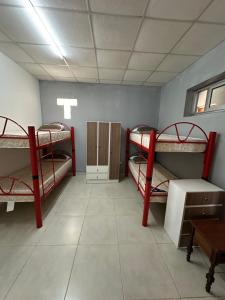 a room with three bunk beds and a table at Hostal Del Sol Temporario in Rosario