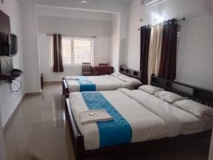 a room with three beds and a television in it at Hotel Mother Palace - Blue Rays in Baindūru