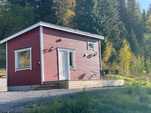 奥勒Solbergs, fint attefallshus i Vik, Åre Ledigt vecka 13!的一栋带门廊和两把椅子的小红房子