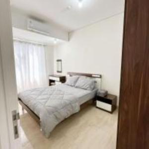 - une chambre blanche avec un lit et une fenêtre dans l'établissement Apartemen Podomoro City Deli Park Medan, à Medan