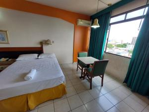 um quarto com uma cama, uma mesa e uma janela em Taj Mahal Hotel em Manaus