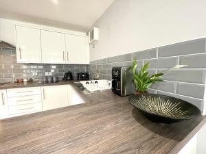 a kitchen with white cabinets and a black bowl on a counter at RNM - Business Professionals Stay, Walsall City Centre, 2 Bedroom with ensuite and bathroom, Entire Place, Kitchen & Washroom with amenities, Smart Tv, Easy Access, Fast WiFi, Parking Nearby, Great transport links in Walsall