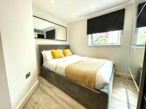 a bedroom with a bed with yellow pillows and a window at RNM - Business Professionals Stay, Walsall City Centre, 2 Bedroom with ensuite and bathroom, Entire Place, Kitchen & Washroom with amenities, Smart Tv, Easy Access, Fast WiFi, Parking Nearby, Great transport links in Walsall +7 photos