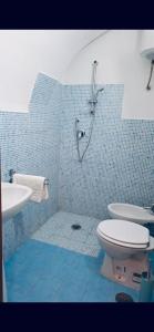 a blue tiled bathroom with a toilet and a sink at Napoli Apartment in Naples