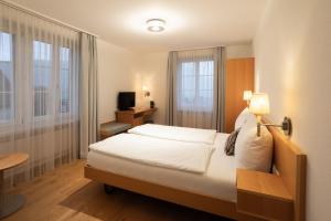 Schlafzimmer mit einem Bett, einem Schreibtisch und einem TV in der Unterkunft Wysses Rössli Swiss Quality Hotel in Schwyz