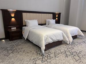 2 camas en una habitación de hotel con sábanas blancas en Grand Plaza Hotel Samarkand, en Samarkand