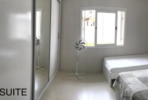 a white bedroom with a bed and a window at Casa em Capao in Capão da Canoa