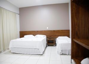 a room with two beds with white sheets at Terras Hotel in Lucas do Rio Verde