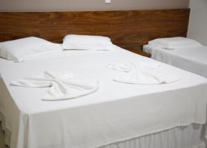 two beds with white sheets and towels on them at Terras Hotel in Lucas do Rio Verde
