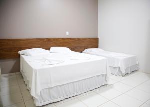 2 bedden in een kamer met witte lakens bij Terras Hotel in Lucas do Rio Verde