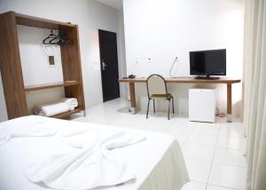 een slaapkamer met een bed, een bureau en een televisie bij Terras Hotel in Lucas do Rio Verde