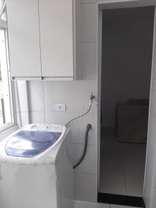 a white bathroom with a toilet and a sink at Apto Guaruja Astúrias in Guarujá