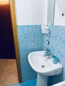 a bathroom with a sink and a blue tiled wall at Napoli Apartment in Naples