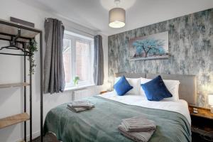 1 dormitorio con 1 cama grande con almohadas azules en 20% Off 4 Bed Home with Driveway and Garden, en Preston
