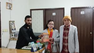 three people standing around a table holding a box at VRINDA Kunj ASHRAYAM in Vrindāvan