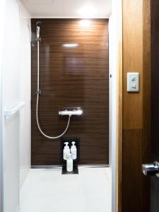 a bathroom with a shower with a wooden wall at 貸切宿にんじん in Hara