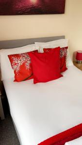 a white bed with red pillows on it at Nick's Place in Plymouth