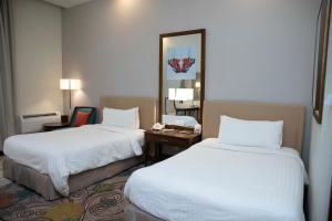 a hotel room with two beds and a mirror at Pearl Continental Hotel, Bhurban in Bhurban