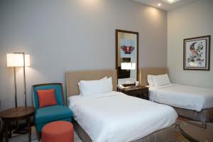 a hotel room with two beds and a chair at Pearl Continental Hotel, Bhurban in Bhurban