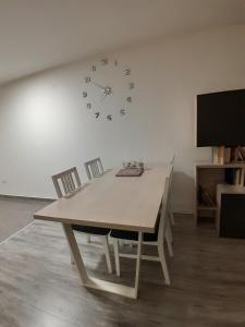 ein Esstisch mit Stühlen und einer Uhr an der Wand in der Unterkunft Inalux Apartmani Pale in Gornje Pale