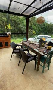 una mesa de madera y sillas en un patio en Casa Container, Vista para o Lago e integrada com a Natureza - Miguel Pereira, en Miguel Pereira