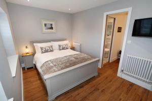 a bedroom with a bed with white walls and wooden floors at Georges Bank in The Mumbles