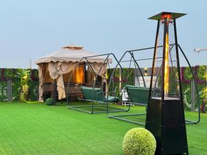 a gazebo with chairs and a swing in a yard at Swat Hotel Apartments 4 in Al Khobar