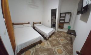 2 camas en una habitación pequeña con suelo en Hotel San Adolfo Carepa, en Carepa