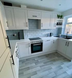 uma cozinha com armários brancos e piso em azulejo em St Blaise em Water Orton