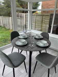 einen schwarzen Tisch mit Stühlen, Tellern und Weingläsern in der Unterkunft St Blaise in Water Orton