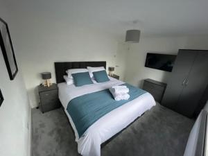 ein Schlafzimmer mit einem großen Bett mit blauen und weißen Kissen in der Unterkunft St Blaise in Water Orton