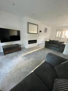 uma sala de estar com um sofá e uma televisão de ecrã plano em St Blaise em Water Orton
